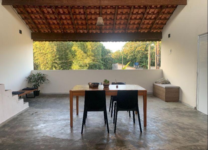 a table and chairs in a room with a large window at Chalé com Varanda Grande e Terraço Vista Mar in Itanhaém