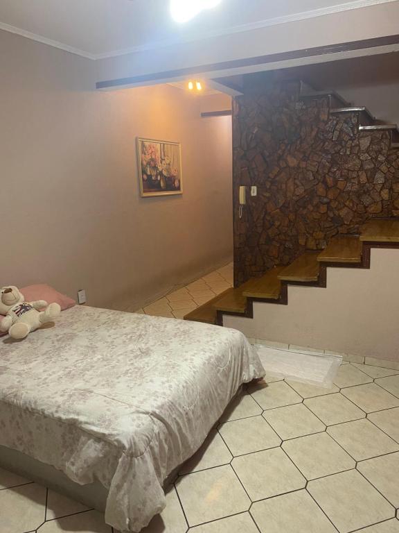 een slaapkamer met een bed en een stenen muur bij Recanto das Maritacas in Votorantim