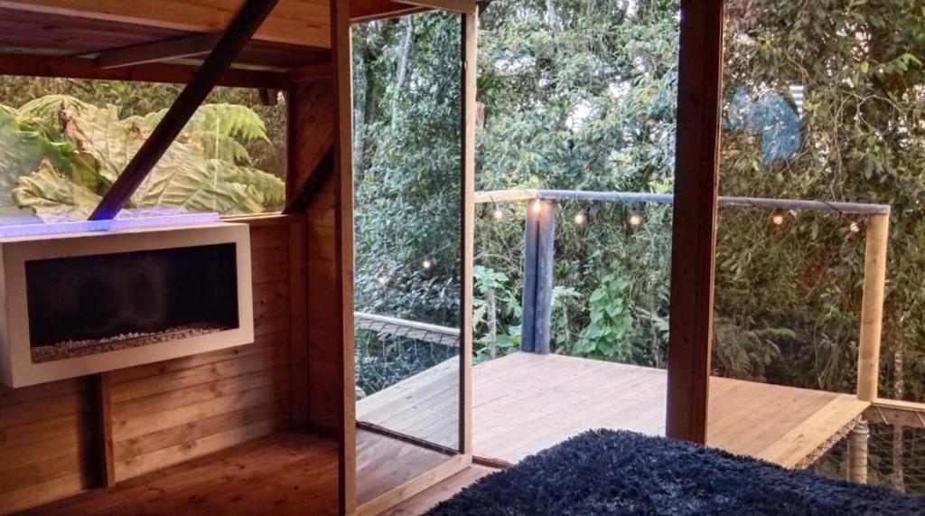 a tiny house with a balcony with a tv at Cabaña Bosquecito Escondido in San Pedro