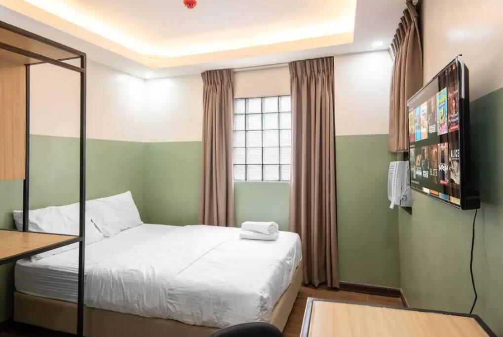 een kleine slaapkamer met een bed en een televisie bij St. Marvin Studio Makati M509 in Manilla