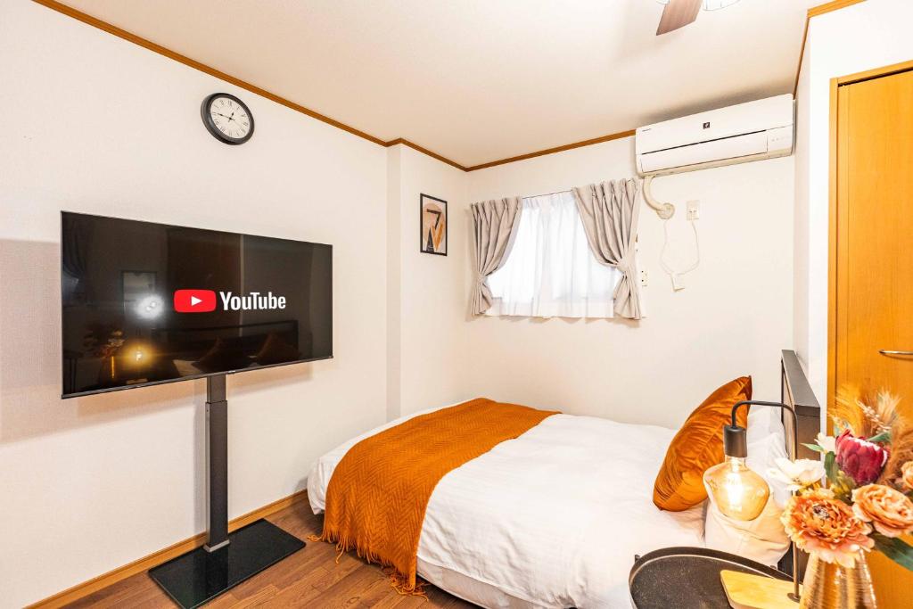 a small bedroom with a bed and a flat screen tv at アリタビル大国 in Osaka