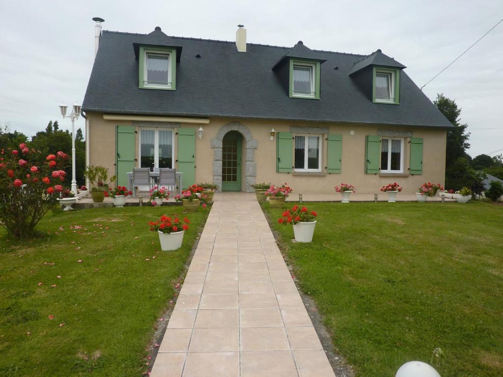 una casa amarilla con techo gris y flores rojas en Chambre D'Hote, en Roz-Landrieux