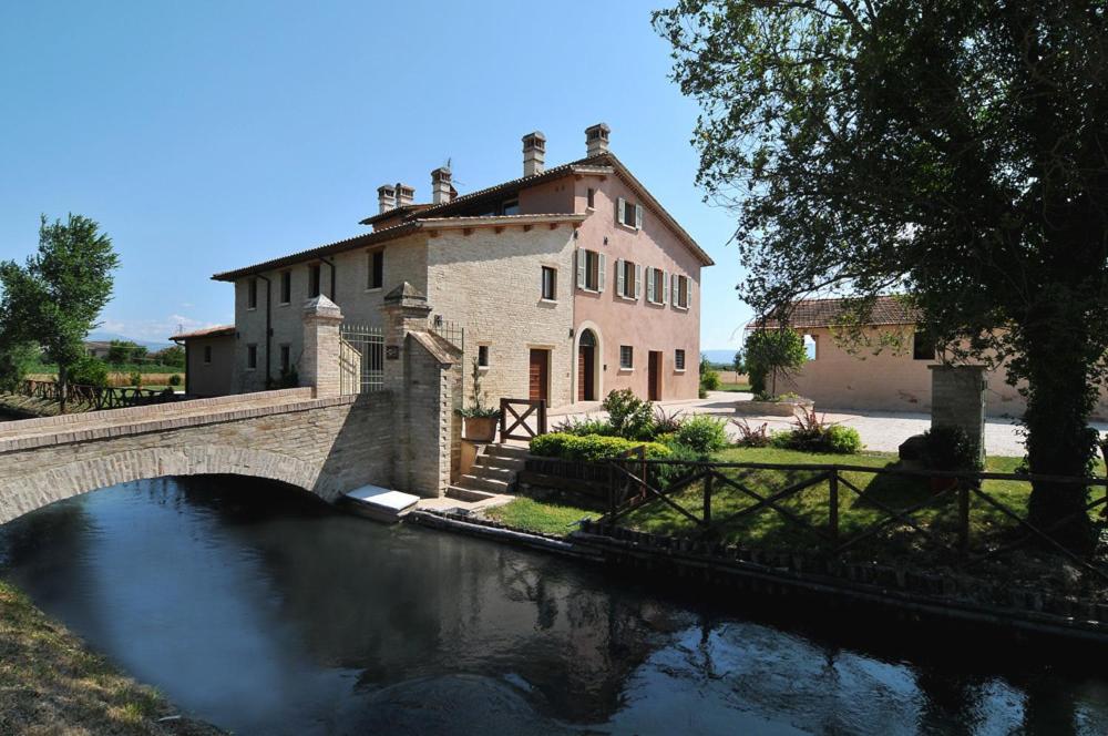 a bridge over a river in front of a building at Country House Casco Dell'Acqua in Trevi