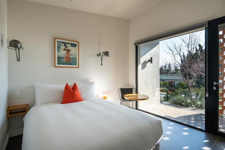 a bedroom with a white bed and a large window at Jejutokki in Seogwipo