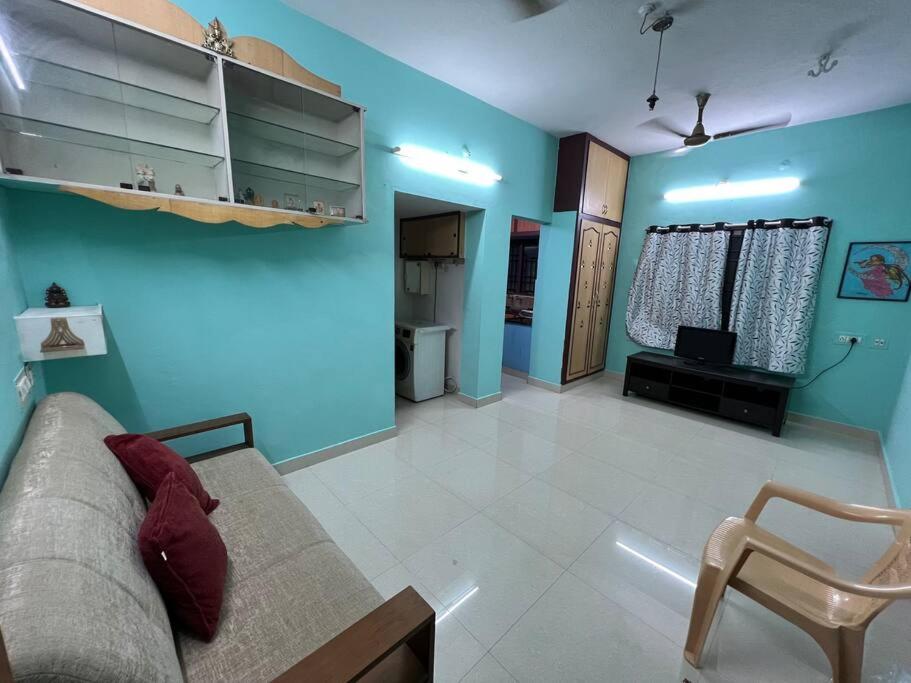 sala de estar con paredes azules, sofá y silla en The best enclave, en Chennai