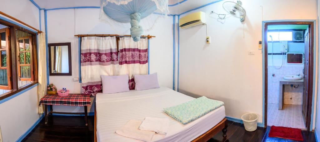 a small room with a bed and a shower at Lao Long Riverside and Budget Garden Guesthouse in Ban Khon