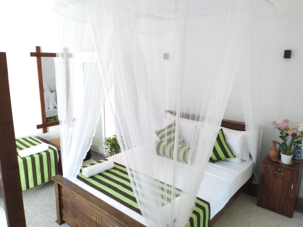 1 dormitorio con cama con dosel y almohadas verdes y blancas en Nethu villa, en Galle