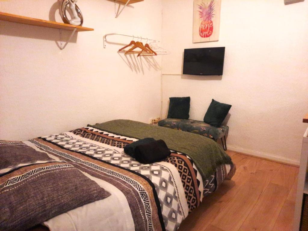 two beds in a room with a tv on the wall at STUDIO avec PARKING TOUT A PIED et CALME in Bandol