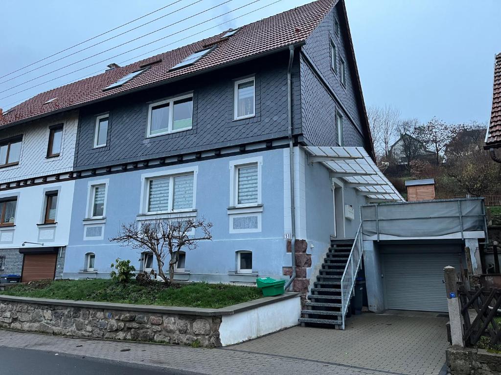 a large blue house with a garage and stairs at Ferienwohnung „Ruppbergblick“ in Zella-Mehlis