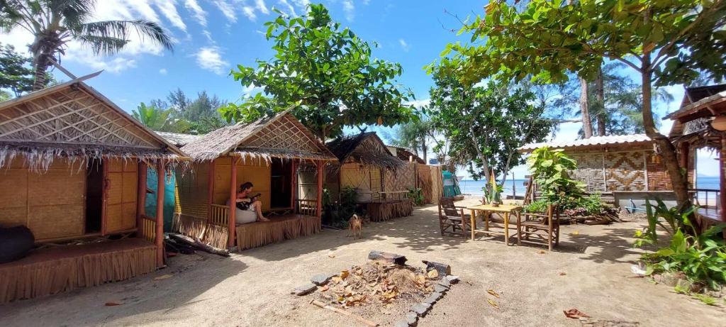 a group of cottages with a woman sitting in the doorway at Little Beach Garden in Ban Ai Dao