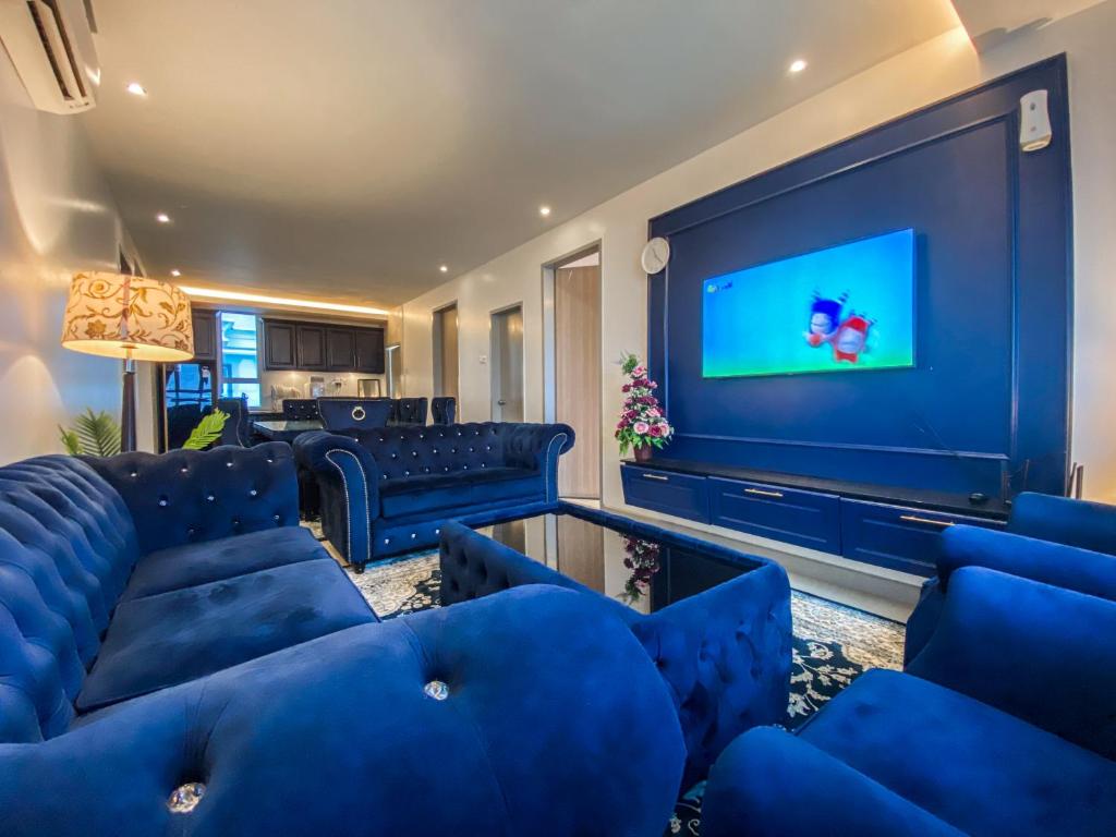 uma sala de estar com mobiliário azul e uma televisão de ecrã grande em D'Grand Homestay Tanjung em Kuala Terengganu