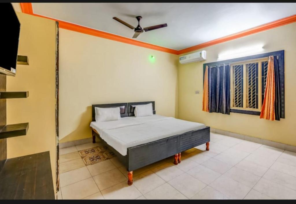 een slaapkamer met een bed en een plafondventilator bij Goroomgo Hotel Moon Chakra Tirtha Road Puri - Excellent Stay with Family, Parking Facilities in Puri