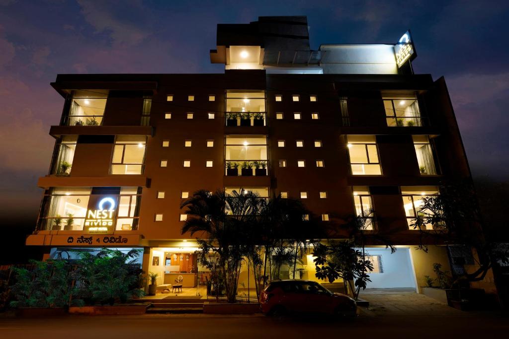 Nest By Rivido Apart Hotel, Bannerghatta road في بانغالور: مبنى متوقف امامه سيارة