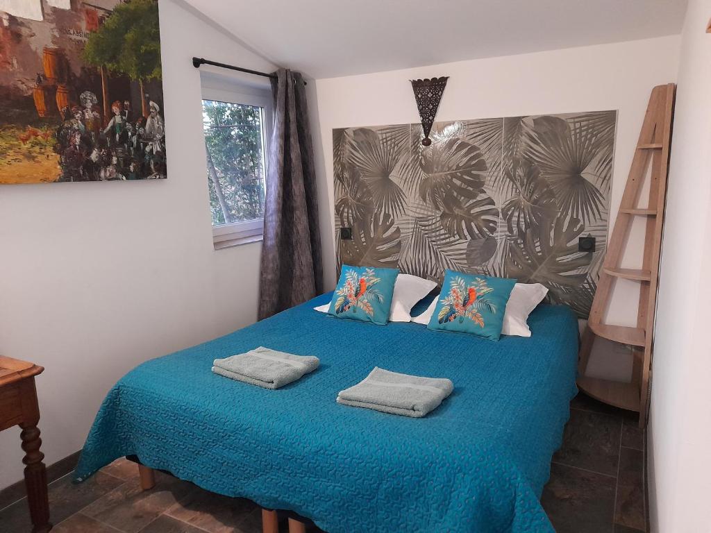 een slaapkamer met een blauw bed met 2 kussens bij le jardin in Montélimar