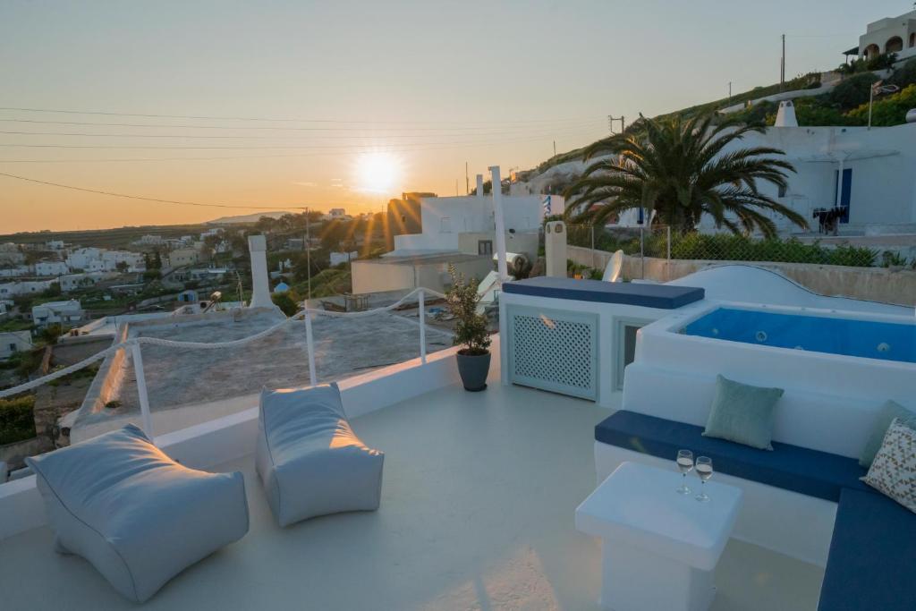 a balcony with blue chairs and the sunset on a hill at Santorini-treasures Rosemary villa traditional in Emporio