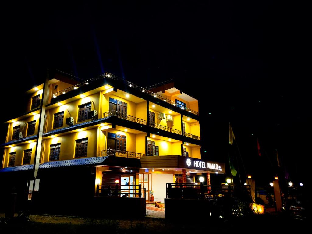 un gran edificio amarillo con luces encendidas por la noche en Hotel Darshan, en Surkhet