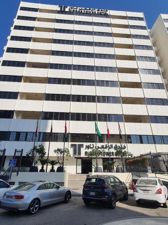 um edifício alto com carros estacionados em frente em Riggae Tower Hotel em Kuwait