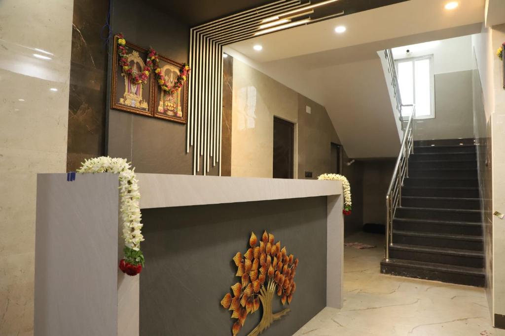 a lobby with a staircase and a wall with flowers at Viruksham Residency in Palani