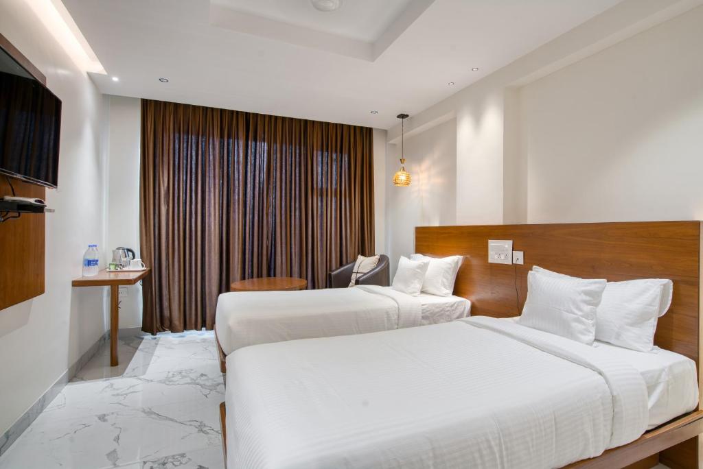 Pokój hotelowy z 2 łóżkami i biurkiem w obiekcie Hotel Vilvah w mieście Coimbatore