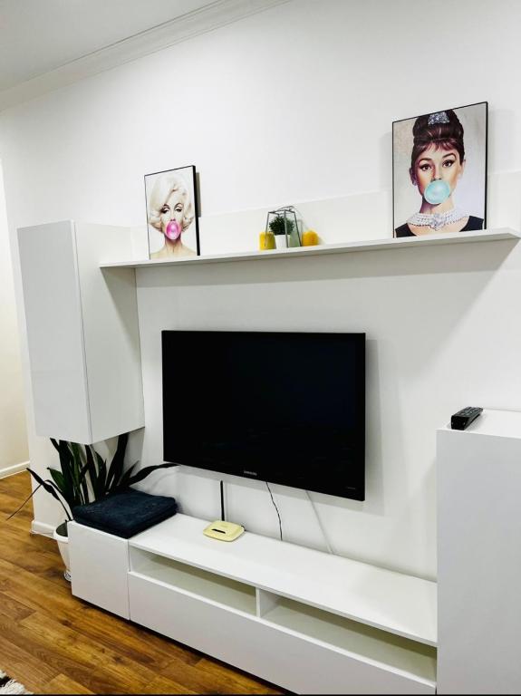 ein weißes Wohnzimmer mit einem Flachbild-TV in der Unterkunft Абая 70 Квартира 7 (Ердена 199) in Sätbaev