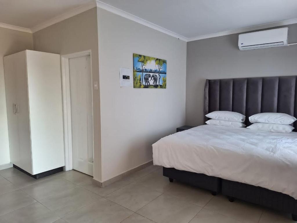 Magomba的住宿－Tree Tops Game Resort，一间卧室配有一张大床和灰色床头板