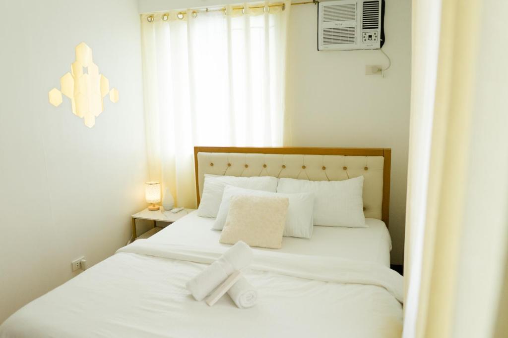 a bedroom with a white bed with a cross on it at Peaceful & quiet 1BR condo w/ pool access, TV&Wifi in Davao City