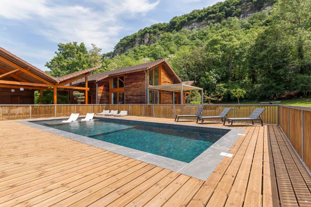 une terrasse en bois avec une piscine et une maison dans l'établissement MAISON GAÏA, à Hières-sur-Amby