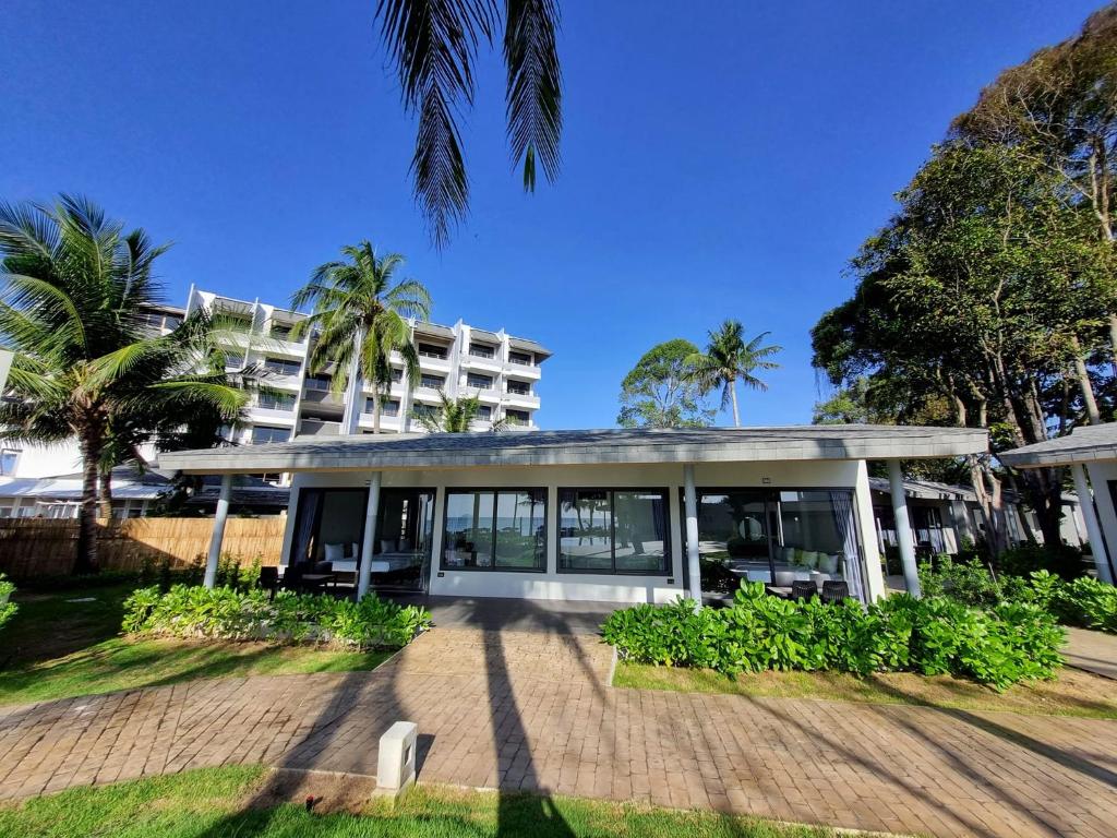 an exterior view of a building with palm trees at Rayong Chalet Hotel And Resort in Klaeng