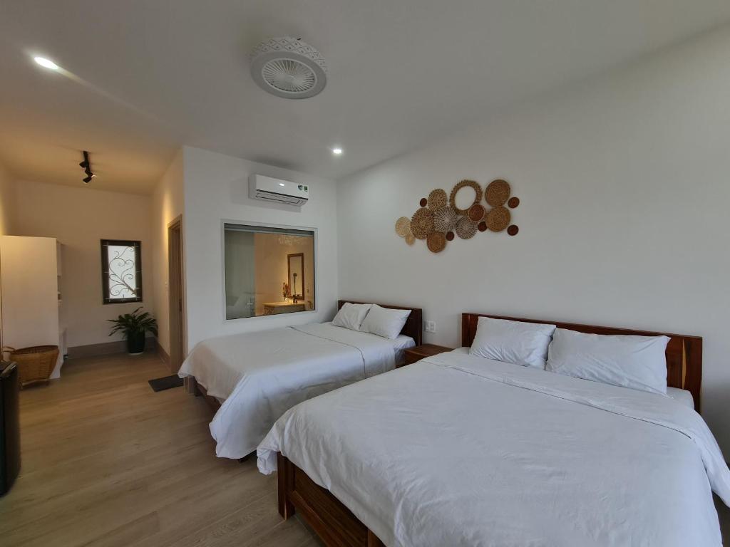 Duas camas num quarto com paredes brancas e pisos em madeira em Myhoa Lagoon - Kiting Town em Phan Rang-Tháp Chàm