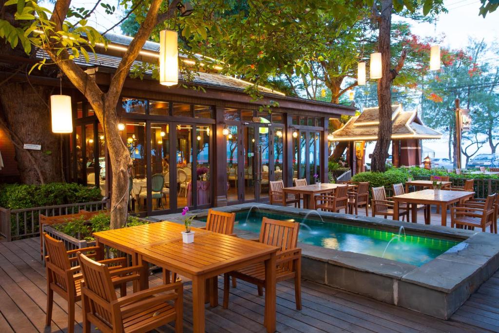 a restaurant with a table and chairs next to a pool at Raya Resort Beach front - The Most Green Resort in Cha-am in Cha Am