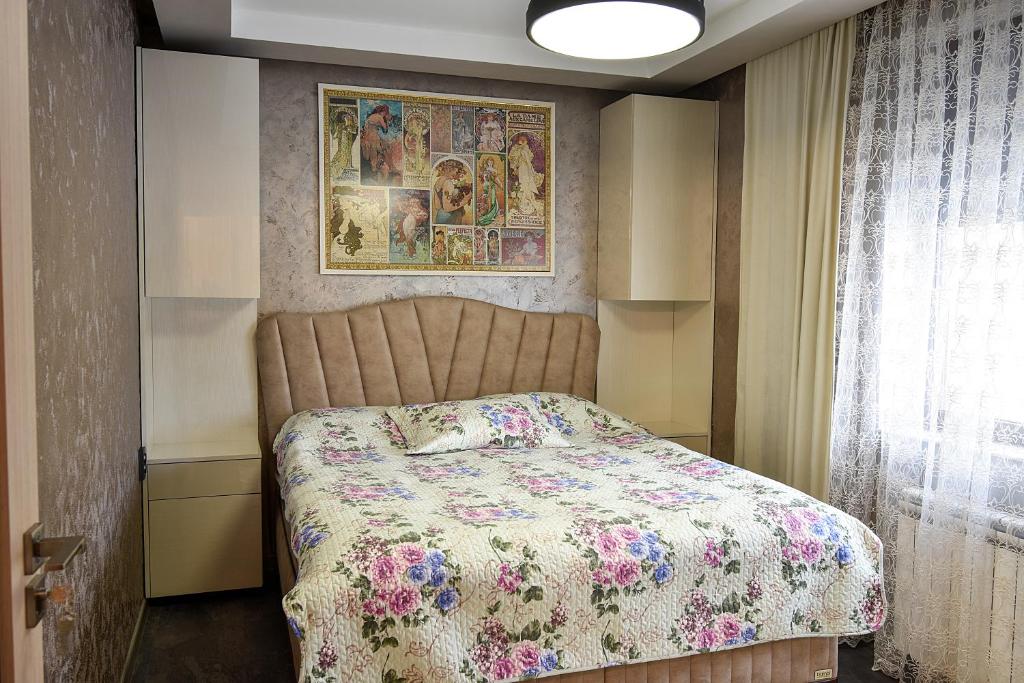 a bedroom with a bed with a floral bedspread at Апартамент Девио in Ruse