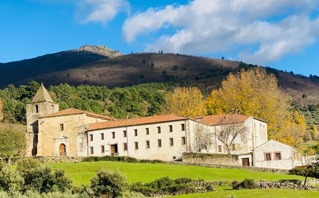 サン・マルティン・デ・トレベホにあるHospedería Conventual Sierra de Gataの山を背景にした畑の古い建物