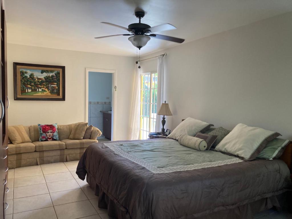 a bedroom with a bed and a couch and a ceiling fan at Hotel y villas palma Real . in La Ceiba