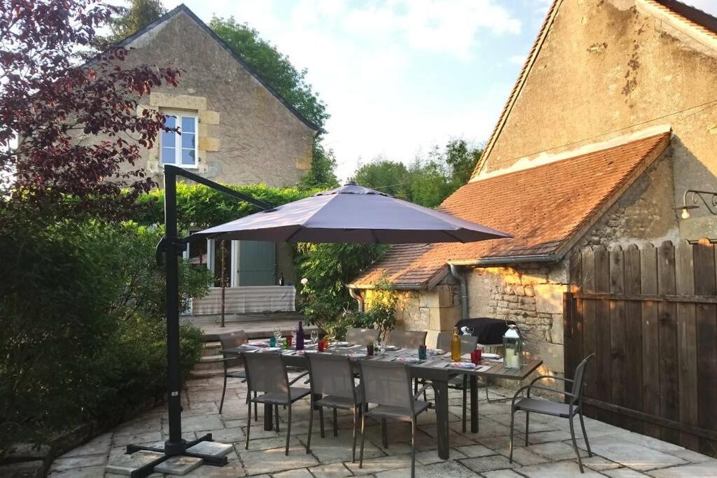 a table with an umbrella on a patio at Maison de charme en Bourgogne in Coulanges-lès-Nevers