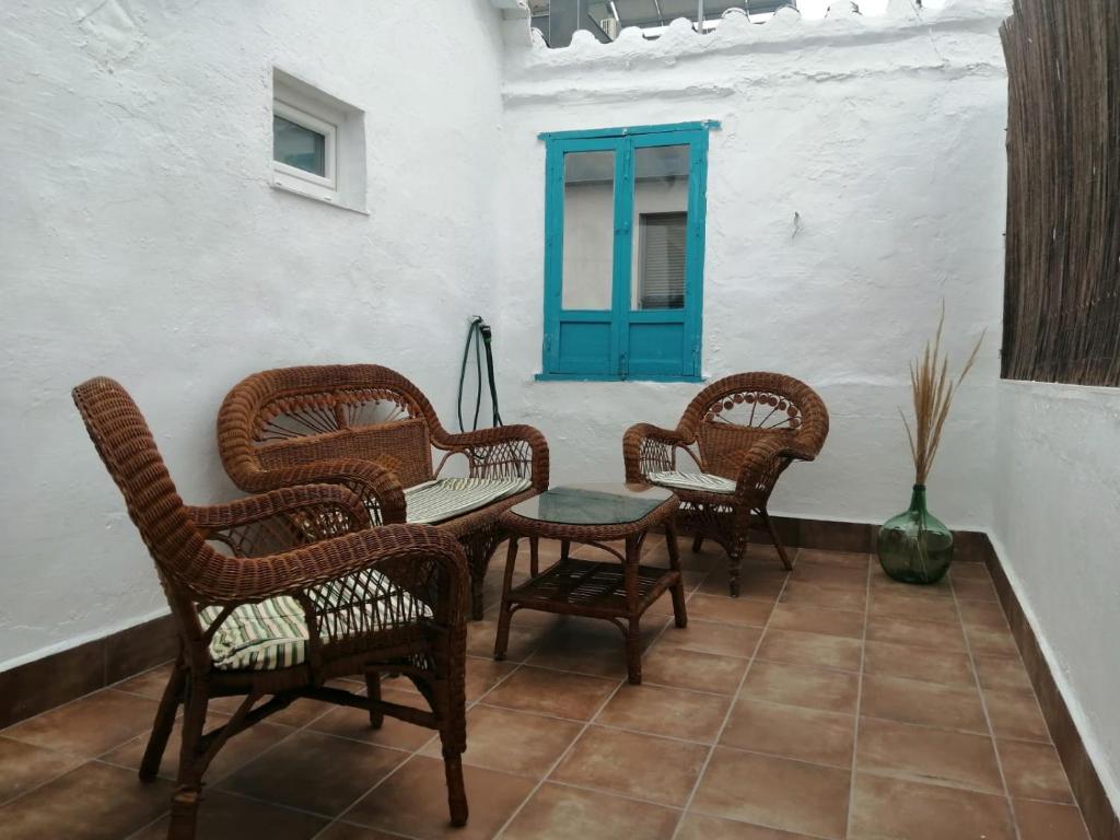 un patio con sillas de mimbre, una mesa y una puerta azul en Casa Rural con Estilo Valdepeñas, en Valdepeñas