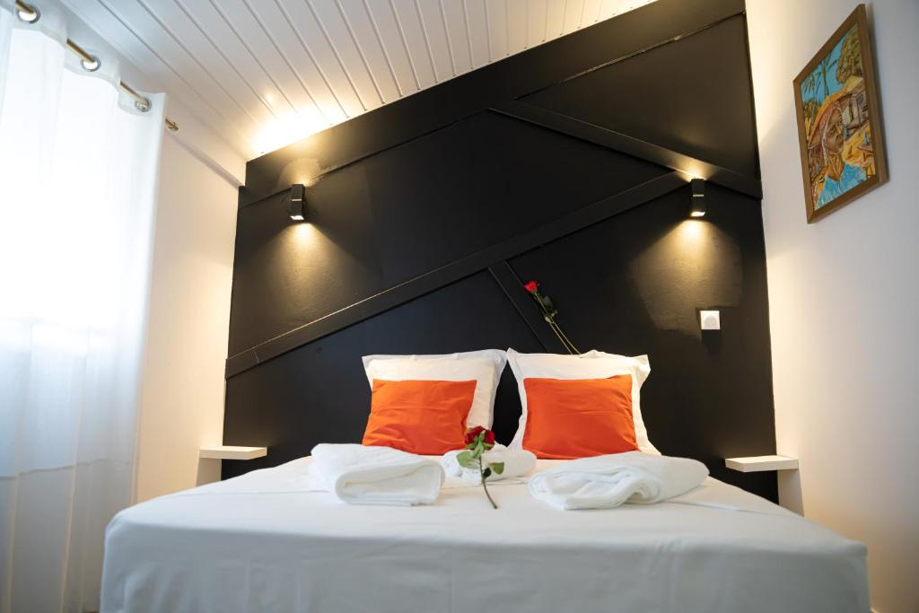 a bed with two orange pillows and a black headboard at L'élégance citadine in Cayenne