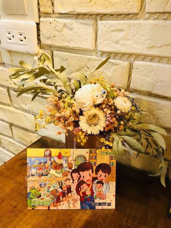 a vase with flowers and a box on a table at 洄瀾雅舍民宿-近火車站-東大門夜市附近 in Hualien City