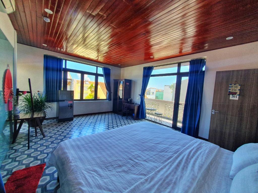 1 dormitorio con 1 cama grande y cortinas azules en Villa De Pi's Hoi An en Hoi An