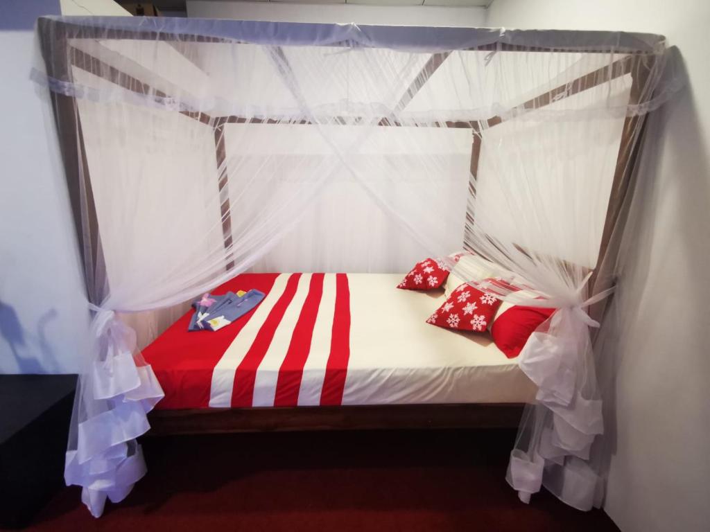 a bed with a canopy with red and white pillows at Villa Sea View in Galle