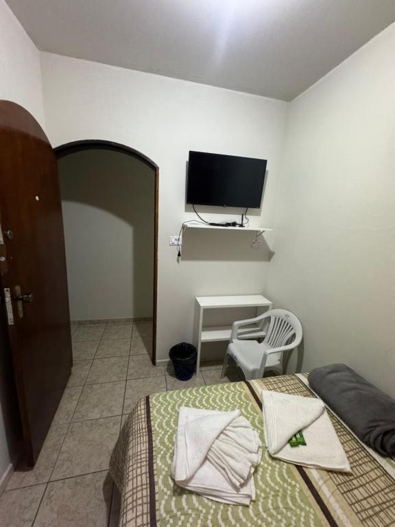 een slaapkamer met een bed en een tv aan de muur bij Quarto Guararema 2 in Guararema