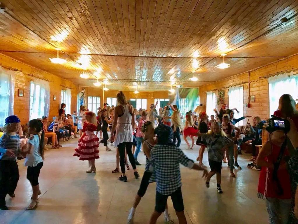 un grupo de niños bailando en una habitación con gente en Едельвейс-Будапешт, en Yasinya