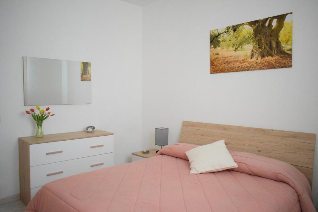 sypialnia z różowym łóżkiem i komodą w obiekcie La Casa del Carrubo w Cagliari