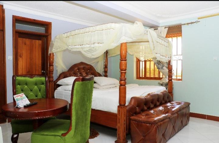 a bedroom with a canopy bed and a table and a chair at PrimeRose Hotel Mubende in Mubende