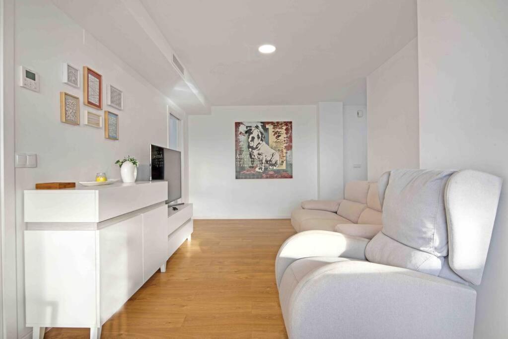 Apartamento atardecer dorado في فالنسيا: غرفة معيشة بيضاء فيها أريكة بيضاء