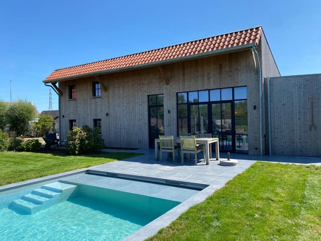 a villa with a swimming pool in front of a house at d'Oude Smidse in Zuienkerke