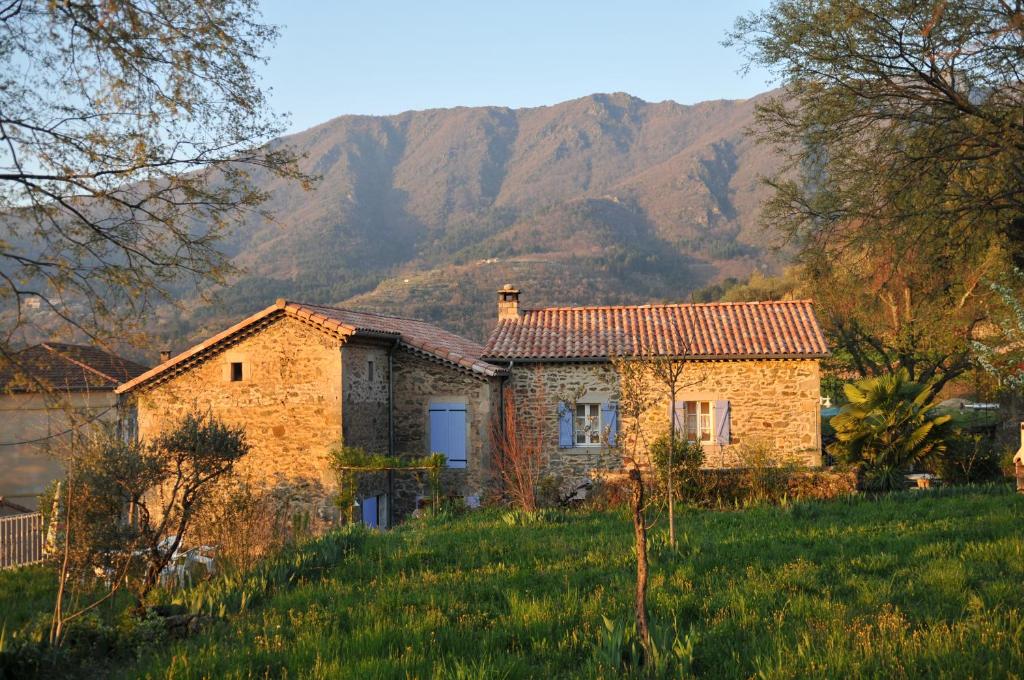 une maison en pierre dans un champ avec des montagnes en arrière-plan dans l'établissement Mas d'Entraygues, à Gravières