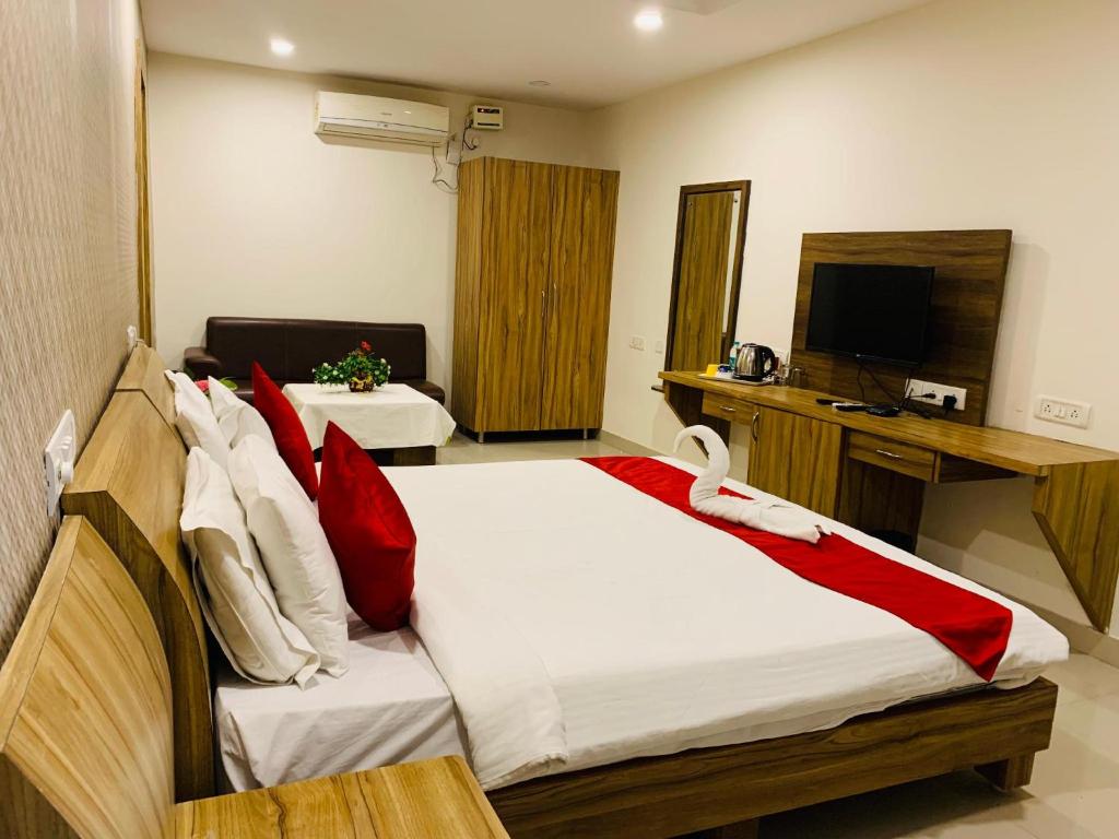 ein Schlafzimmer mit einem großen Bett und einem TV in der Unterkunft The Landmark Banjara Hills - Hyderabad in Hyderabad