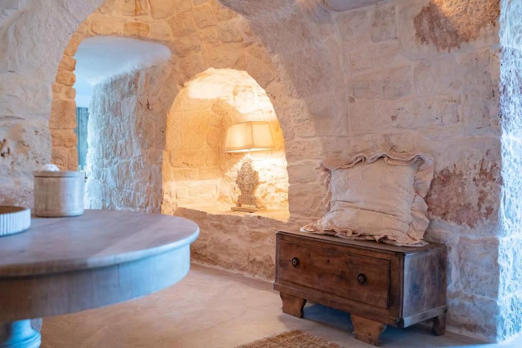 Cette chambre dispose d'une table et d'un mur en pierre. dans l'établissement Trullo Elaia - Dimora di charme in Valle d'Itria con piscina, à Ceglie Messapica