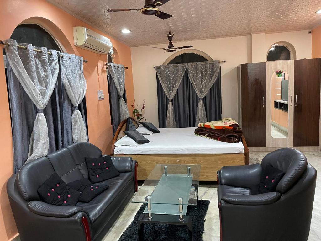 a bedroom with a bed and two leather chairs at Hotel Swarg in Muzaffarpur