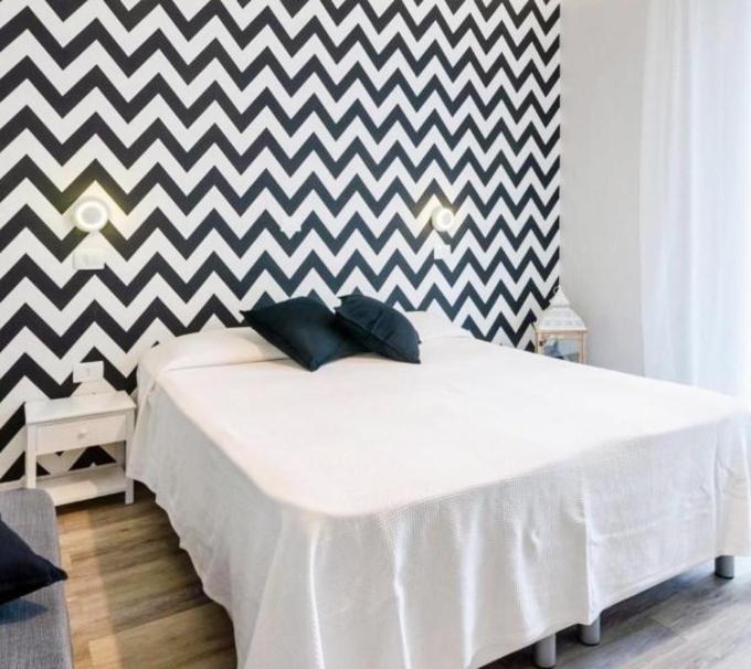 un letto bianco in una stanza con parete a scacchi di Appartamenti Mar y Sol a Gabicce Mare